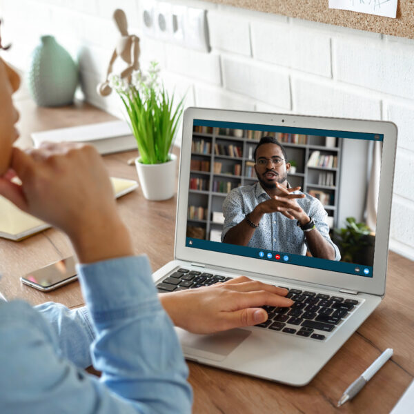 African girl student watching video course, distance e-learning, studying with online teacher by webcam. Remote education, work from home concept. Over shoulder close up laptop mock up screen view.